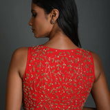Model wearing red sleeveless blouse in georgette fabric with hand embroidery and V-neck