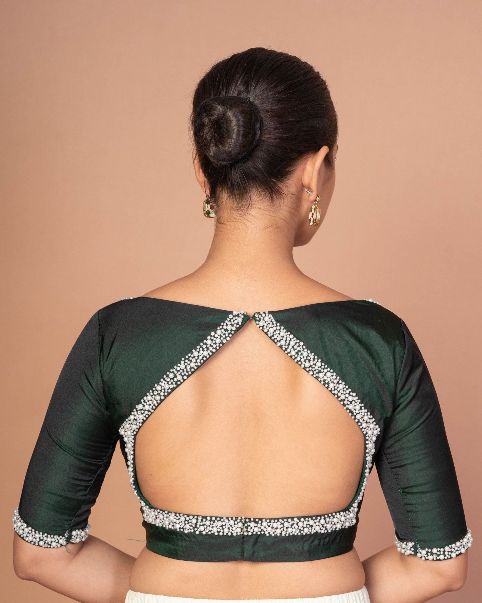 Back view of dark green silk blouse showing pearl-studded cut-out back design