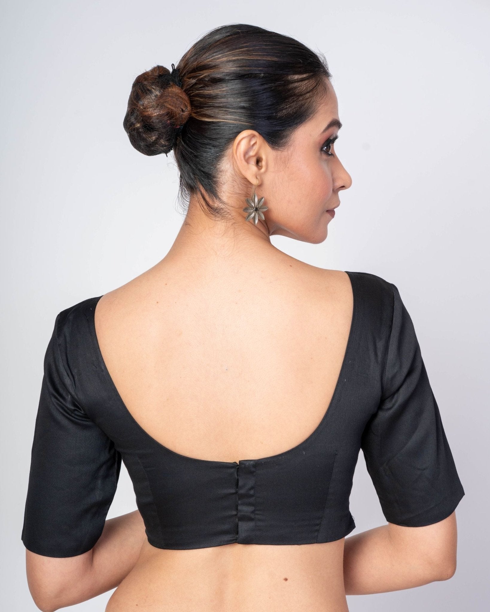 Close-up of the back closure on a black U-neck blouse showing premium stitching and a clean high-quality finish