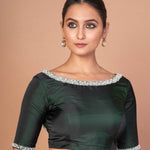 Close-up of hand embroidery and pearl detailing on dark green silk blouse