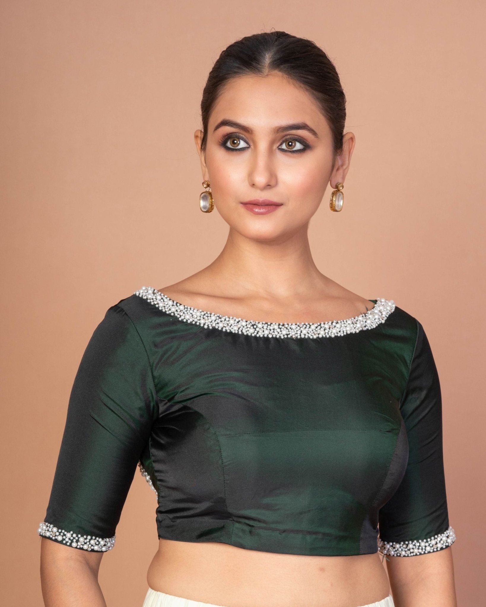 Close-up of hand embroidery and pearl detailing on dark green silk blouse