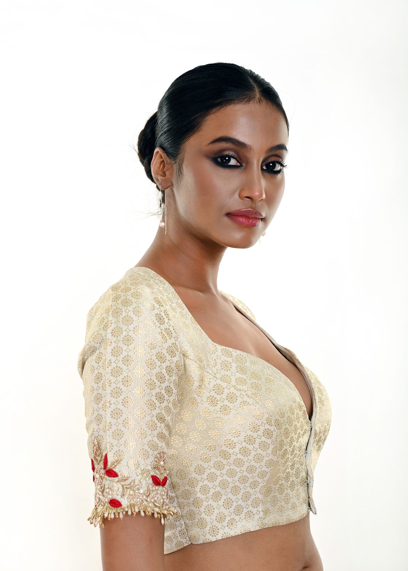 Close-up of hand embroidery detailing on white brocade fabric