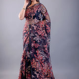 Model in black tissue silk saree with subtle sheer texture and all-over printed floral pattern, with delicate shimmer finish, shown with sample blouse — party and festive wear