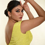 Side profile of lemon yellow satin boat neck blouse showing sleeveless silhouette