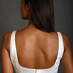 White sleeveless blouse styled with high-waisted trousers for a casual chic look