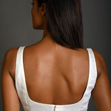 White sleeveless blouse styled with high-waisted trousers for a casual chic look