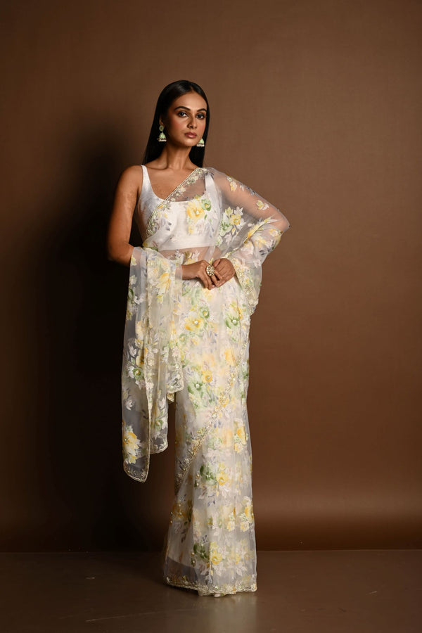 Woman draped in white net saree with all-over multicoloured floral embroidery and cutdana-studded border, styled for festive wear