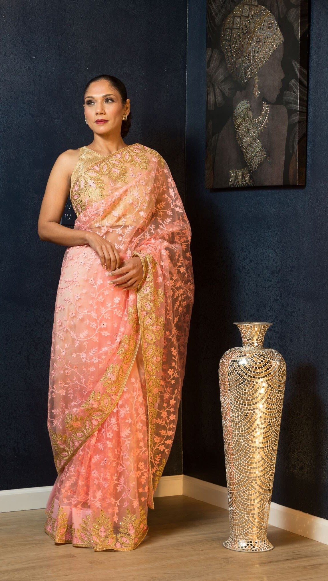 Model wearing a deep pink net saree with dense sequin embroidery in large floral motifs, featuring stonework, suitable for cocktail and reception occasions